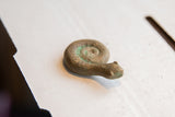 Vintage African curled snake figurine's textured head and coiled body with green patina.