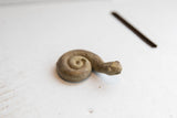 Side profile of a vintage African snake figurine showing its coiled form and textured finish.
