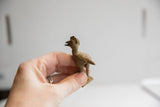 Profile of a small, handmade African crowned bird, held to show its size and etched details.