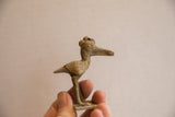 A small handmade African crowned bird figurine held to show scale and textured details.