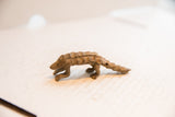 Angled view of the vintage pangolin figurine's segmented, scaled back and rustic form.
