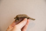 Small vintage pangolin figurine with a rustic finish held in hand for scale.