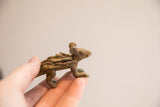 Side view of a vintage porcupine figurine held in hand to show its small size and textured finish.