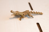 Side view of the vintage crocodile figurine highlighting its textured casting and open snout.