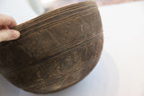 Hand holding antique African carved wooden bowl, highlighting dark brown incised geometric patterns.