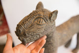 Detailed, textured head of a vintage African leopard casting, held by hand.