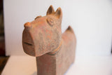 Angled view of the dog sculpture's face, showing its weathered, handmade texture and carved eyes.