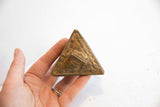 Textured bronze side of the vintage African triangle box with intricate time turner design.