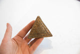 Textured bottom edge of vintage African triangle box, highlighting coiled sun design.