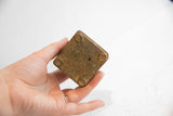 The underside of a vintage African box, showing its rustic, textured base and four small feet.