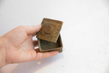Vintage African square box with bronze patina held open to show scale and interior.