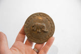 Vintage African circle box lid held in hand to show its scale and aged texture.