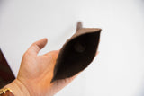 The dark, textured interior and internal clapper of a vintage Yoruba bell.
