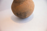 Earthy texture and dark patina on the rounded body of an antique terracotta vase.