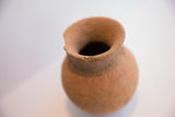 The rough, irregular rim and dark opening of a handmade antique terracotta vase.