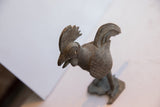Overhead perspective of the vintage rooster sculpture's textured head and oxidized body.
