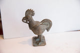 Side angle of a vintage African rooster sculpture with a lightly oxidized, textured finish.