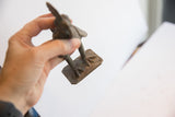 Detailed view of the vintage rooster sculpture's oxidized metal base and textured feet.