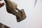 View of the textured underside and square base of the vintage African bird casting.