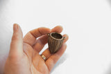 The woven texture and hollow opening of the vintage bronze basket pendant held in hand.