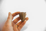 A hand holds the vintage African bronze basket pendant to show its scale.