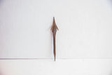 Antique Yoruba spear point standing vertically to show its three-dimensional forged form.