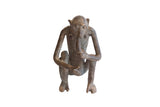 Vintage African monkey figurine eating a banana, with a dark, rustic handmade texture.