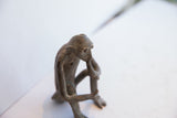 Profile view of a vintage monkey figurine, detailing its pensive face and aged texture.