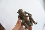 Angled view of the vintage monkey figurine's seated pose and textured, aged patina.