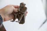 Vintage monkey figurine held in hand to show its small scale and patina.