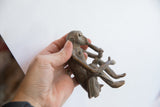 Handmade monkey figurine held in hand to show its scale and textured patina.