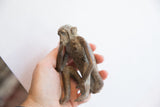 Vintage African monkey sculpture with aged patina held in hand to show scale.