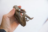 Side profile of the vintage monkey figurine held to show its scale and patina.