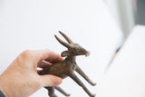 Vintage antelope sculpture held to show its scale and aged, rustic texture.