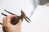 A hand holding the vintage antelope sculpture, showing its textured, aged patina.