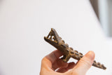 Angled profile of a vintage alligator sculpture showing its open jaws and textured body.
