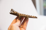 Vintage African alligator sculpture held in hand, showing its textured profile and scale.