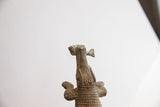 Detail of the vintage alligator's head from below, holding a small fish in its open jaw.
