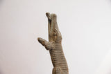 Detailed carving on the head of a vintage alligator sculpture with a fish in its mouth.