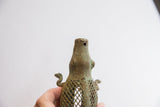 The ribbed head and criss-cross latticework of a vintage African alligator sculpture.