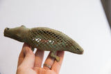 Profile view of the patinated bronze alligator sculpture held in hand for scale.
