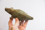 Aged green patina on the textured, checked back of a handmade alligator sculpture.