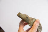 Upward view of the vintage alligator's carved head showing its textured green patina.