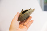 Vintage African fish casting held to show scale and its textured bronze and green patina.