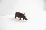 Angled view of the dark patina hippo figurine, showing its simple, handmade form.