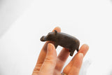 Vintage dark patina hippo figurine held in hand, showing its handmade, petite scale.
