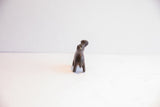 Rear view of a dark patina hippo figurine showing its stout form and handmade texture.
