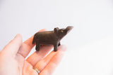 Small dark patina hippo figurine with head tilted up, held in hand.