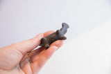Angled view of the small vintage hippo figurine showing its handmade shape and dark patina.