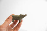 Small vintage African hippo figurine with a dark oxidized patina held in hand.